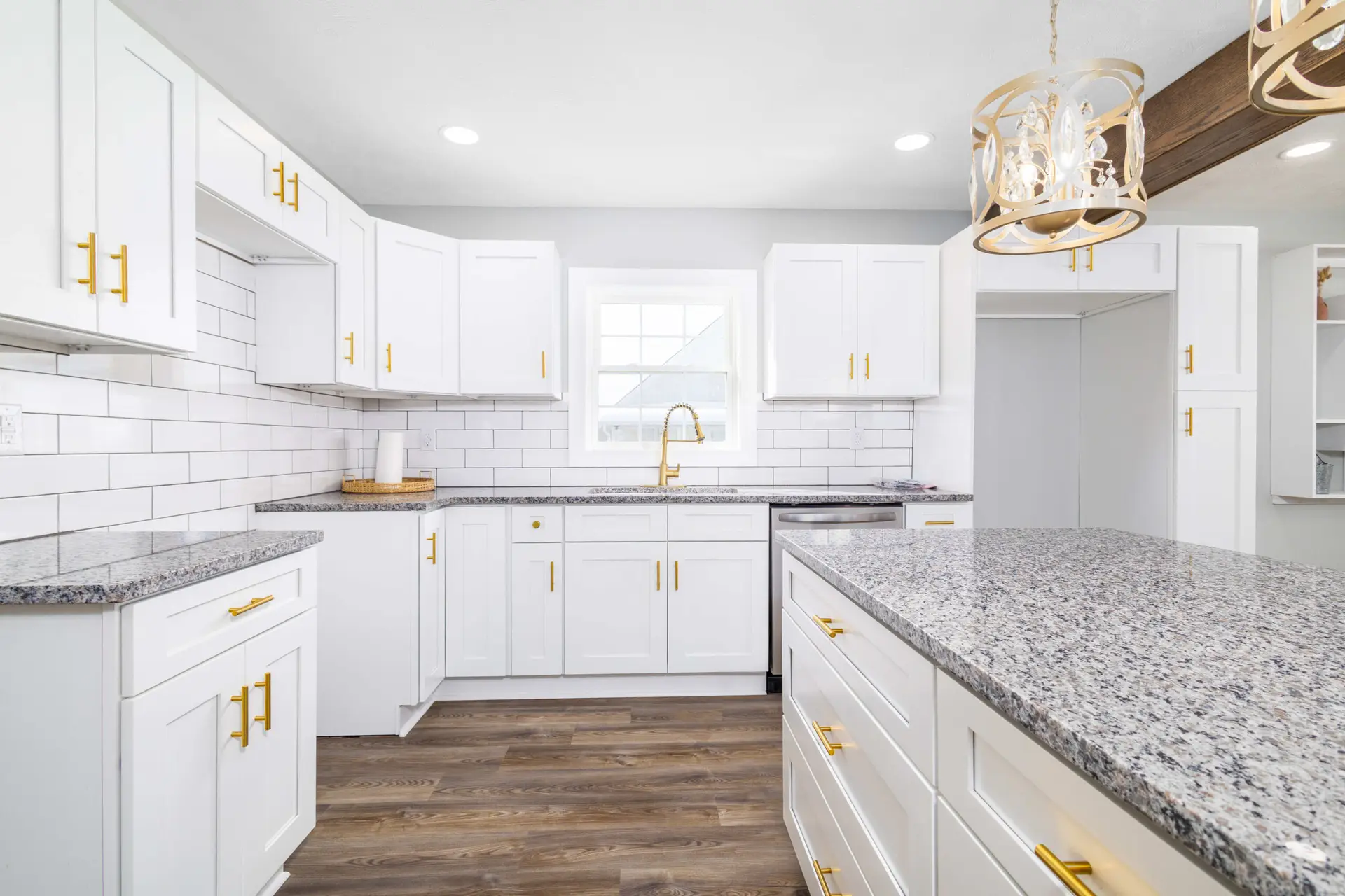 White shaker kitchen with granite island and brushed gold pendant lighting