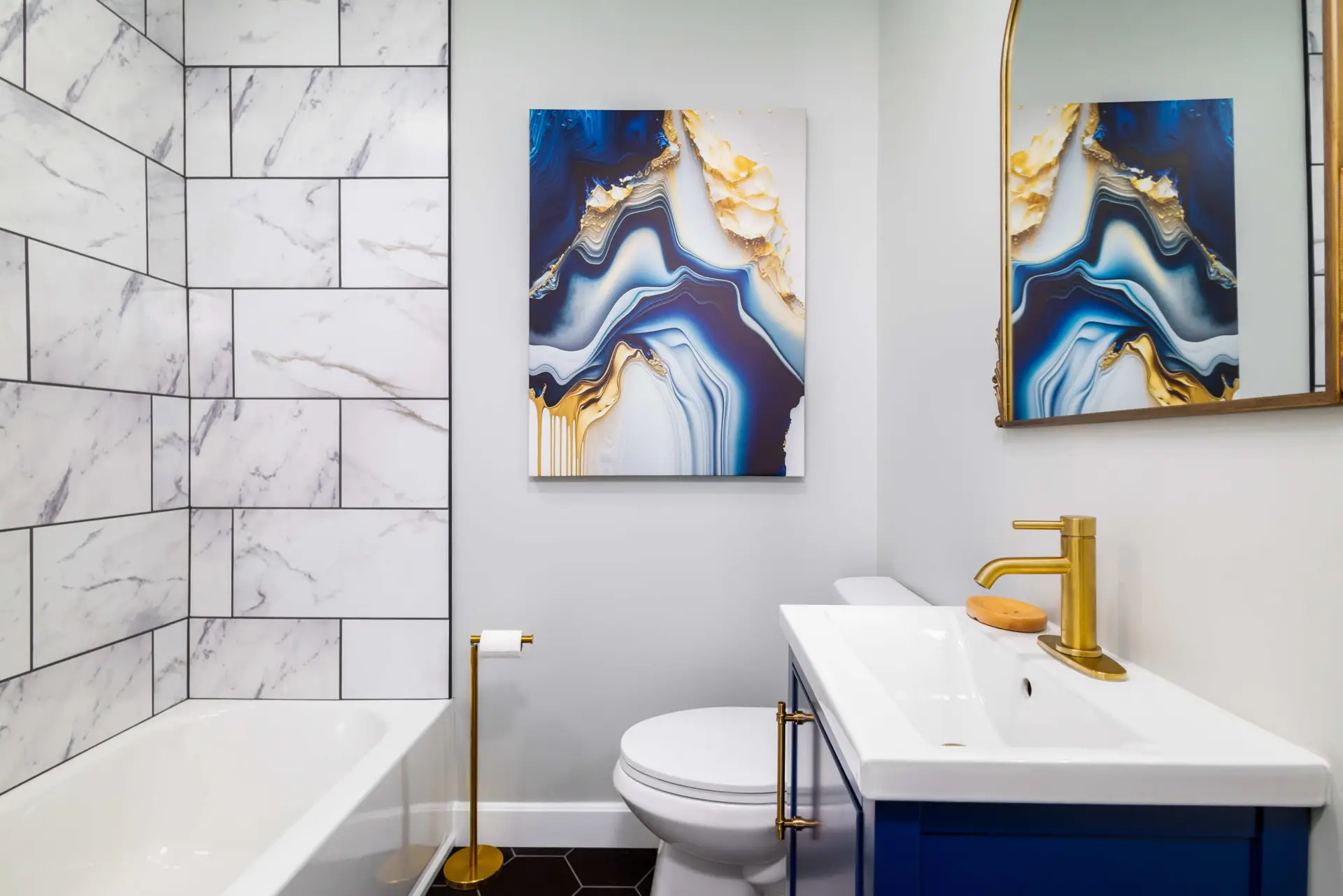 Blue vanity powder bath with marble subway tile and gold fixtures